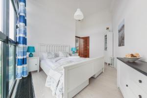 a white bedroom with a bed and a window at Apartamenty Sun & Snow Dune A in Mielno