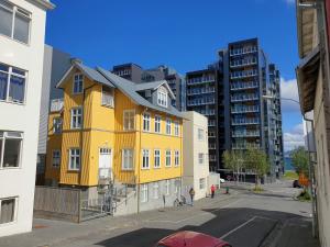 un bâtiment jaune dans une rue avec de grands bâtiments dans l'établissement Alfred's Studios, à Reykjavik