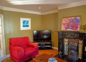 a living room with a red chair and a television at Dingle Town Holiday Home in Dingle