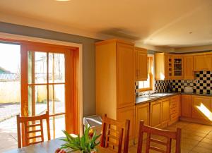 a kitchen with wooden cabinets and a table with chairs at Dingle Town Holiday Home in Dingle
