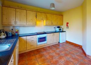 uma cozinha com armários de madeira e piso em azulejo em Seacliff HH No 8 em Dunmore East