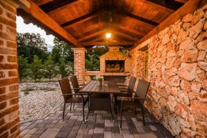 un patio con mesa de madera y sillas en una pared de piedra en Villa Plasa Krk en Kras