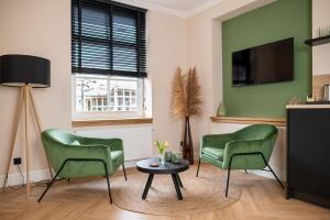 a living room with two green chairs and a table at Bed en Baguette in Burgh Haamstede