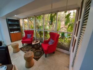 a living room with two red chairs and a large window at Angel Hotel in Lagos