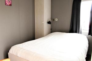 una camera da letto con un letto bianco con una finestra di Hofgalow Chalet op camping "De Stal" a Drijber