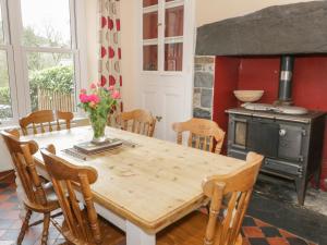 a dining room with a wooden table and a stove at Ty Capel in Betws-y-coed