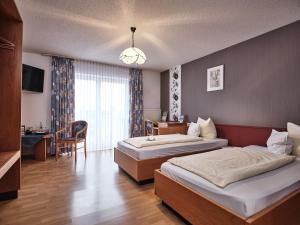 a hotel room with two beds and a table and a desk at TIPTOP Hotel am Hochrhein in Bad Säckingen
