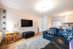 uma sala de estar com um sofá de couro preto e uma televisão em Burlington Place, Shrewsbury. 2 bedroom, private parking, 5 minutes from town em Shrewsbury