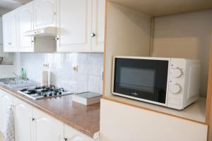 a white kitchen with a microwave and a stove at West Side Roses appartement in Ostend