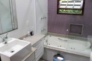 y baño con lavabo, bañera y espejo. en Casa Incrível em Nova Friburgo - Espaço Humedica, en Nova Friburgo