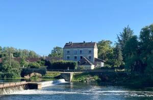 un gran edificio blanco sentado junto a un río en Les Gites Du Moulin Du Port, en Saint-Georges-sur-Cher