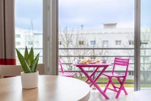 a pink table and chairs in a room with a window at Comfort Aparthotel Le Mans in Le Mans