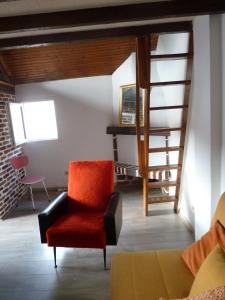 a living room with a red chair and stairs at La Petite maison en Sologne in Salbris +6 photos