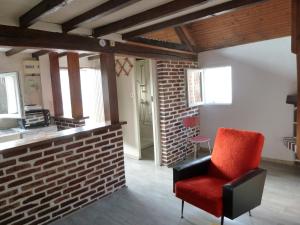 una silla roja en una habitación con una pared de ladrillo en La Petite maison en Sologne, en Salbris
