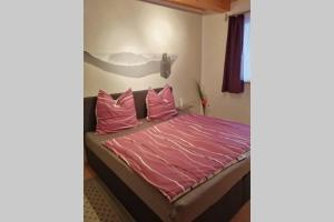 um quarto com uma cama com lençóis e almofadas cor-de-rosa em Quartier am Markt- Ferienwohnung em Bad Gottleuba