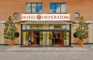 a hotel entrance with two potted trees in front of it at Hotel IMPERATORI in Rome