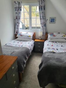 two twin beds in a room with a window at 20 Tudor Court " Four Star AA accommodation" in Hayle