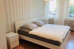 Cama con sábanas blancas y almohadas junto a una ventana en Apartment 120 qm -3 Schlafzimmer-2 Bäder- für 8 Gäste, en Düsseldorf