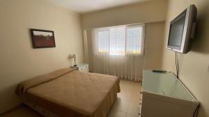 Departamentos Premium - 2 Ambientes - Excelente ubicación في ميرامار: غرفة نوم مع سرير وتلفزيون بشاشة مسطحة