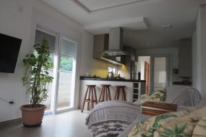 ein Wohnzimmer mit einem Sofa und einer Küche in der Unterkunft CASA NOVA CONFORTÁVEL E ACONCHEGANTE in Garopaba