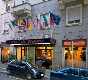 un'auto parcheggiata di fronte a un edificio con bandiere di Hotel Pavone a Milano