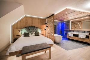 una camera con un grande letto e una vasca da bagno di Majestic Hotel & Spa Resort a Brunico