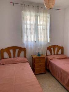 a bedroom with two beds and a table with a lamp at El Castell Orange Costa in Alcossebre