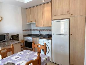 a kitchen with a table and a white refrigerator at El Castell Orange Costa in Alcossebre