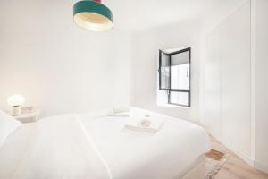 een witte slaapkamer met een wit bed en een raam bij Comfy Apartment by Olala Homes in Cascais