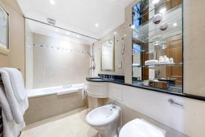 a bathroom with a toilet and a tub and a sink at Cheval Knightsbridge in London +116 photos