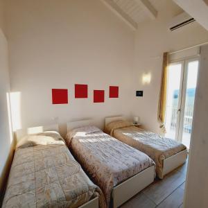 2 Betten in einem Zimmer mit roten Bildern an der Wand in der Unterkunft Villaggio Esmera in Desenzano del Garda