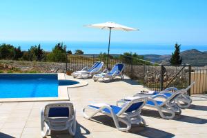 a group of chairs and an umbrella next to a swimming pool at Luxury Villa Price with private pool near Dubrovnik in Ivanica