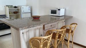 Departamentos Premium Miramar في ميرامار: مطبخ مع كونتر مع كراسي وميكروويف