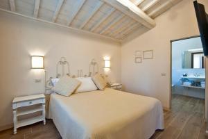 a white bedroom with a bed and a window at Fattoria Pieve a Salti in Buonconvento