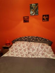 a bed in a bedroom with an orange wall at Diófa Kuckó Apartman in Zalakaros
