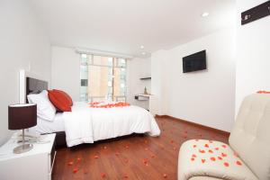 a white bedroom with two beds and a chair at Hotel Castellana 100 in Bogotá