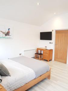 Schlafzimmer mit einem Bett, einem Schreibtisch und einem TV in der Unterkunft Wyvern Apartment in Yeovil