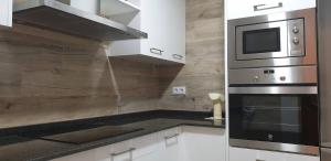 eine Küche mit Herd und Mikrowelle in der Unterkunft PISO MONTERO RÍOS 18 in Cangas