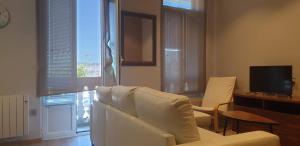 ein Wohnzimmer mit einem weißen Sofa und einem Fernseher in der Unterkunft PISO MONTERO RÍOS 18 in Cangas