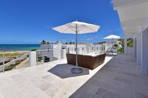 un patio con sombrilla, sillas y el océano en Coral Beach Club Villas & Marina en Dawn Beach