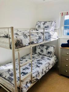 a bedroom with three bunk beds with blue and white at Ruby Willow’s in Pembrokeshire