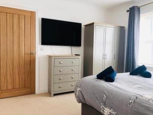 a bedroom with a bed and a television on a dresser at Ruby Willow’s in Pembrokeshire