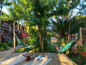 a hammock in the middle of a garden with trees at Hotel Pousada Marambaia in Arraial d'Ajuda