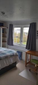 a bedroom with a bed and a desk and windows at Homely Haven, Dunfermline in Dunfermline