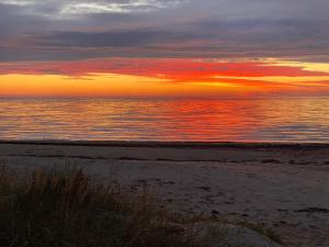 una puesta de sol en una playa con el océano y el cielo en Milleri, en Salacgrīva