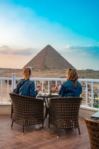 Dos mujeres sentadas en una mesa frente a la pirámide. en Marvel Stone Hotel, en El Cairo