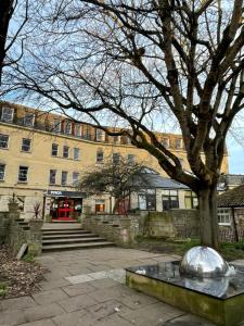 a building with a tree and a silver ball on a bench at Bath YMCA Hostel in Bath