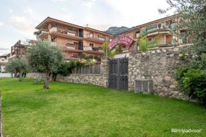 ein Gebäude mit einer Steinmauer und einem grünen Hof in der Unterkunft Taormina Hotel Calipso in Mazzeo