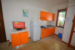 リニャーノ・サッビアドーロにあるLignano with poolのキッチン(オレンジ色のキャビネット、白い冷蔵庫付)