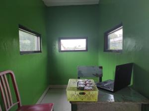 a green room with a desk with a laptop on it at OYO 90333 Wisma Tenang Jaya Syariah in Majalengka